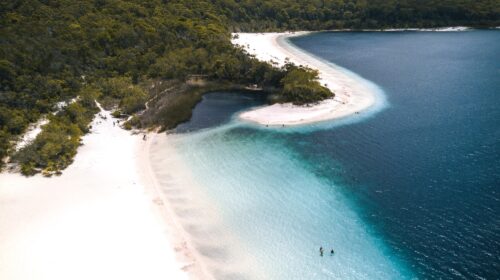 Aerial photo of Lake Mackenzie's shore with trees in the background and a group of swimmers