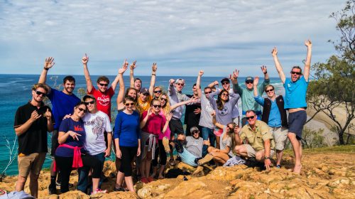 A group photo of a tour group standing in front of the ocean