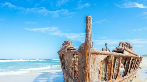 A close up of a shipwreck with a blue sky above it