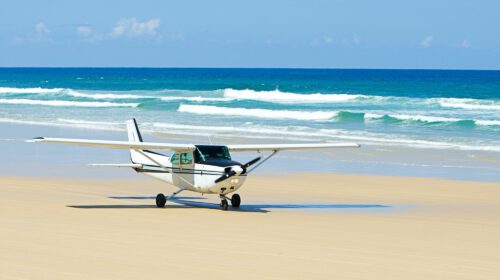 A small plane parked on the sand of a beach