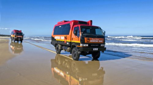 Two tour vehicles driving along a beach