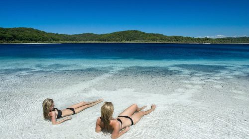 Two people laying in the shallow water of Lake Birrabeen