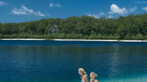 Two people running in shallow lake water