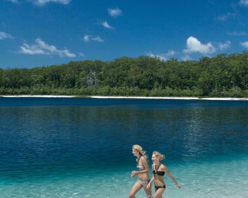 Two people running in shallow lake water
